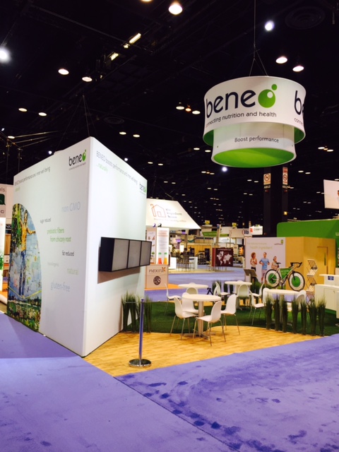 Beneo booth wall panel with product claims and mounted screens beside cafe seating