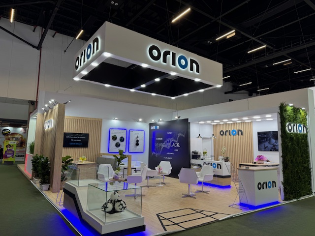 Orion booth with wood-slat walls, greenery, and illuminated hanging ceiling structure