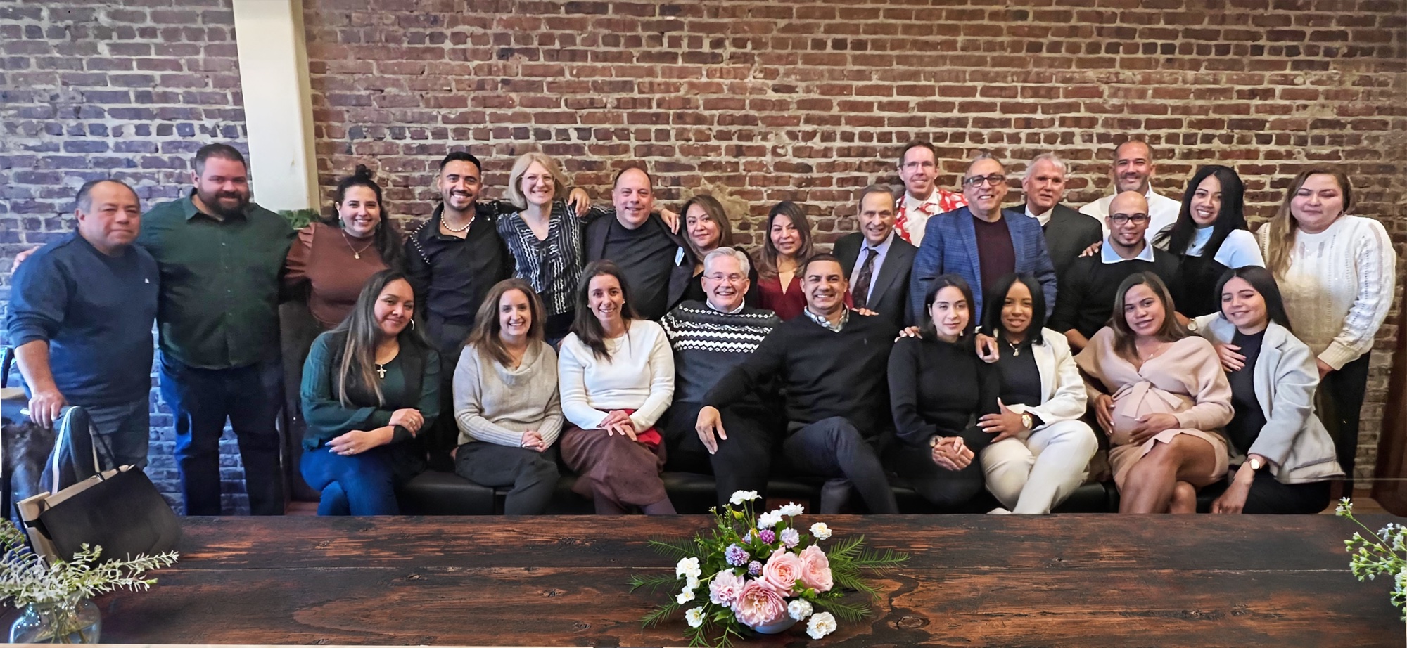 The full HAP Marketing team gathered together in front of a brick wall at a company celebration