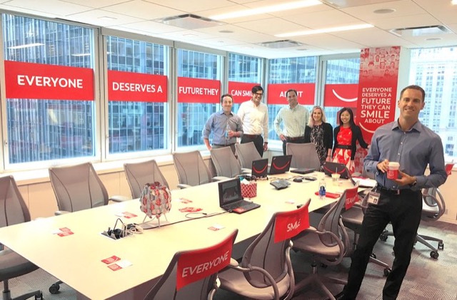 Smiling team in a conference room decorated with red branded window banners and chair covers